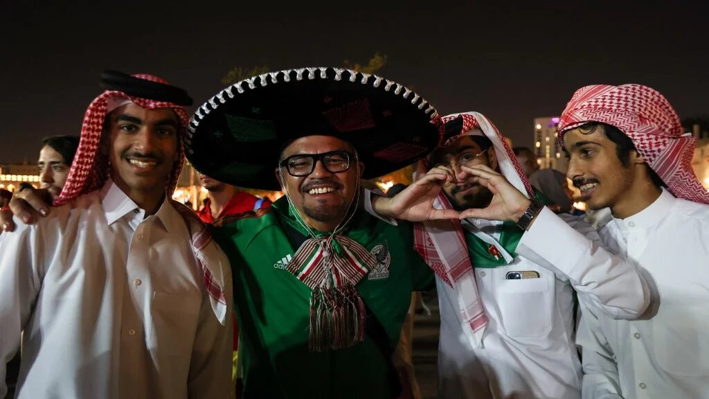 A Mexico fan posing with Saudi Arabia supporters
