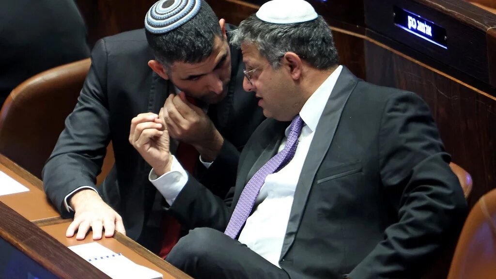 Israeli Knesset member Itamar Ben-Gvir (R) speaks with the Likud party's Shlomo Karhi (L) during a session to elect the new speaker of the assembly in Jerusalem on 13 December 2022 (AFP)