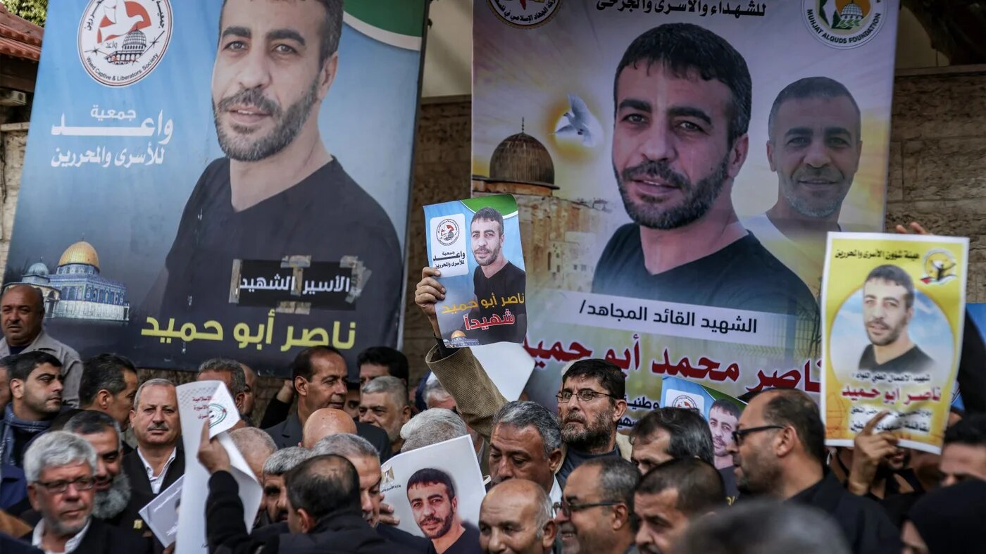 People gather with photos of Palestinian Nasser Abu Hamid for a protest outside the International Committee of the Red Cross (ICRC) mission headquarters in Gaza City on December 20, 2022 (AFP)