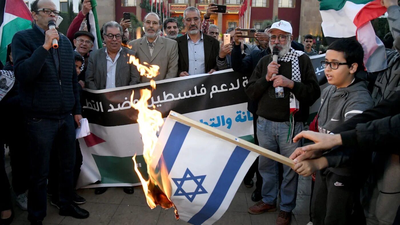 Moroccans burn the Israeli flag as they gather to protest the normalisation of ties with Israel, outside the parliament building in the capital Rabat on December 24, 2022 (AFP)