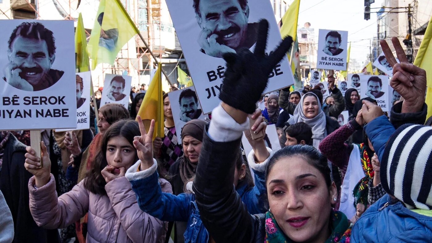 Protesters raise yellow flags and portraits showing the face of Abdullah Ocalan, the leader of the Kurdistan Worker's Party (PKK) -- jailed in Turkey since 1999 -- during a demonstration calling for his release, in the Kurdish-majority city of Qamishli in northeastern Syria on February 15, 2023 (AFP)