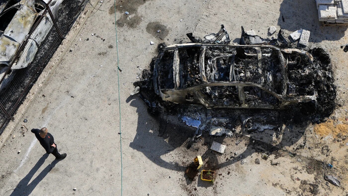 A Palestinian looks at a torched car in the occupied West Bank town of Huwara on 27 February 2023 following violent settler riots (AFP)