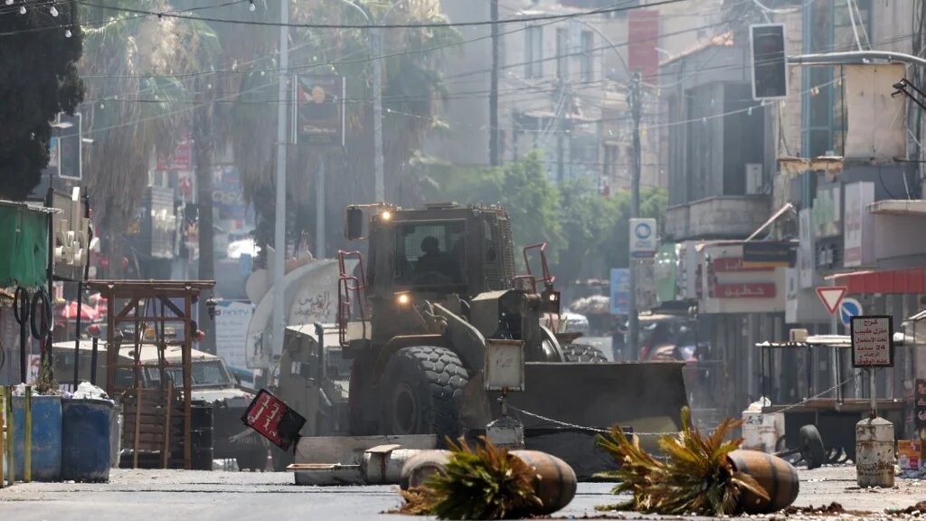 An Israeli army bulldozer drives through Jenin in the occupied West Bank during a military operation on 3 July (AFP)