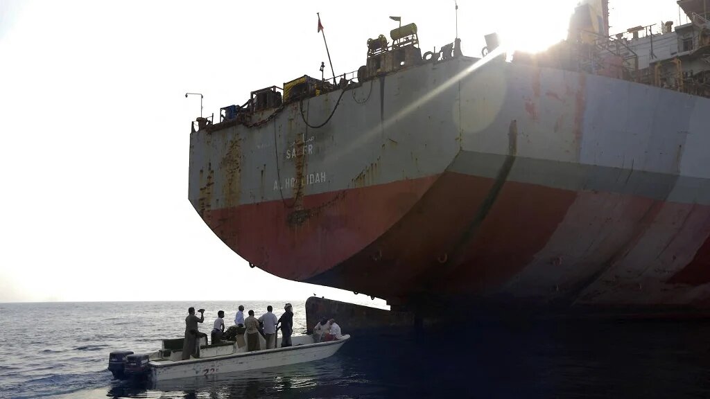Des personnes à bord d’un petit bateau s’approchent du pétrolier FSO Safer, battant pavillon yéménite, en mer Rouge, au large de la province occidentale contestée de Hodeïda, le 15 juillet 2023 (AFP/Mohammed Huwais)