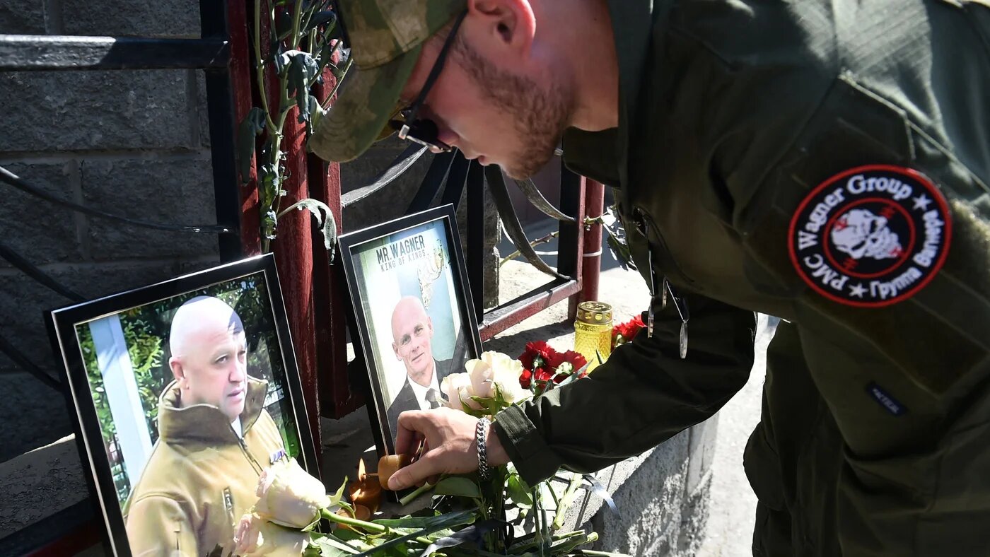A member of private mercenary group Wagner pays tribute to Yevgeny Prigozhin (L) and Dmitry Utkin, a shadowy figure who managed Wagner's operations and allegedly served in Russian military intelligence, at the makeshift memorial in front of the PMC Wagner office in Novosibirsk, on August 24, 2023 (AFP)