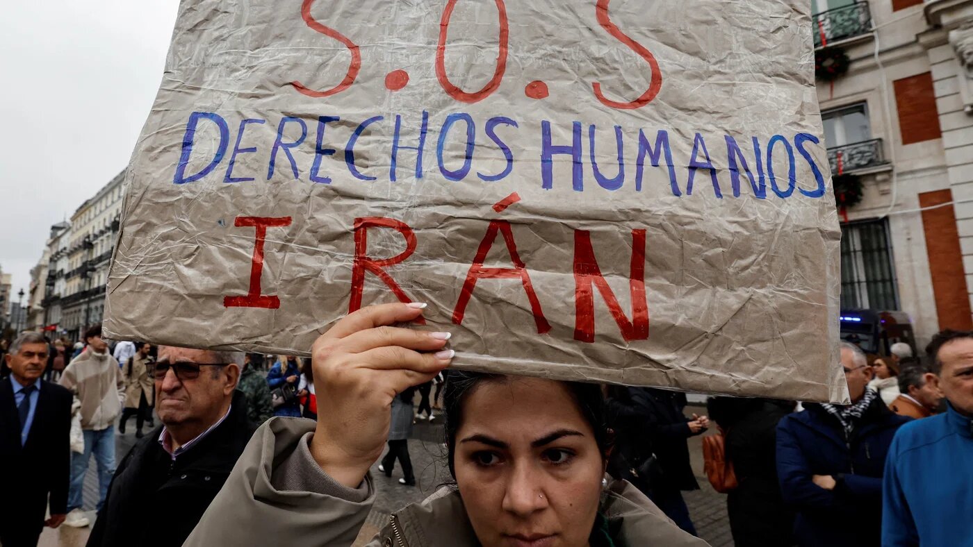 A protestor holds a sign reading "SOS Human rights Iran" during a demonstration called for the Human Rights to Peace, in Madrid, on December 10, 2023 (Oscar Del Pozo/AFP)