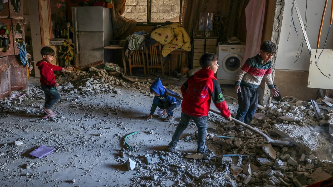 Palestinian children collect small pieces of debris following Israeli bombardment in Rafah in the southern Gaza Strip on 22 December 2023 (Mohammed Abed/AFP)
