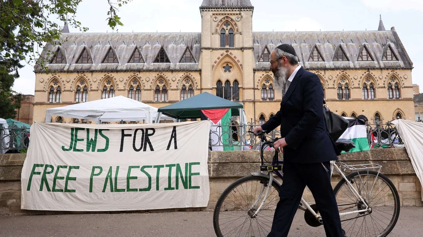 A passerby wearing a kippa pushes his bicycle past a banner reading "Jews for a free Palestine" at Oxford University in Oxford, eastern England (AFP)