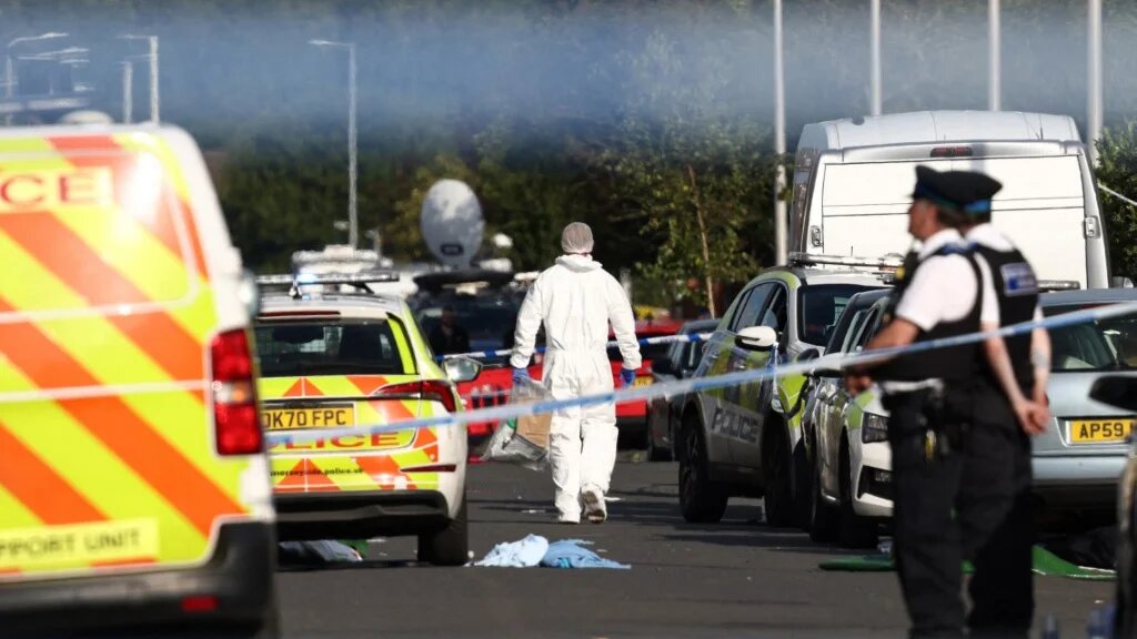 Police officers and forensic personnel stand behind a cordon on Hart Street in Southport, northwest England, on July 29, 2024