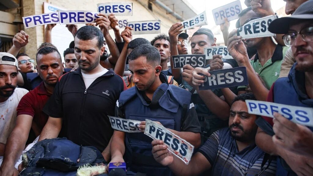 Mourners and colleagues holding 'press' signs surround the body of Al-Jazeera Arabic journalist Ismail al-Ghoul, killed along with his cameraman Rami al-Refee in an Israeli strike in Gaza, on July 31, 2024. (AFP)