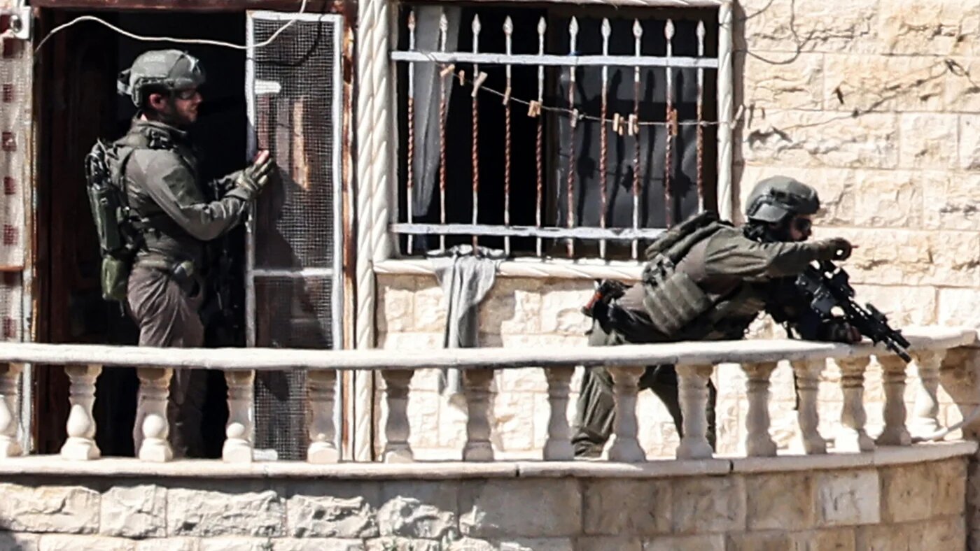 Israeli army soldiers take position in the balcony of a building while surrounding another during an army raid in Qabatiyah south of Jenin in the occupied West Bank on 19 September 2024 (Zain Jaafar/AFP)