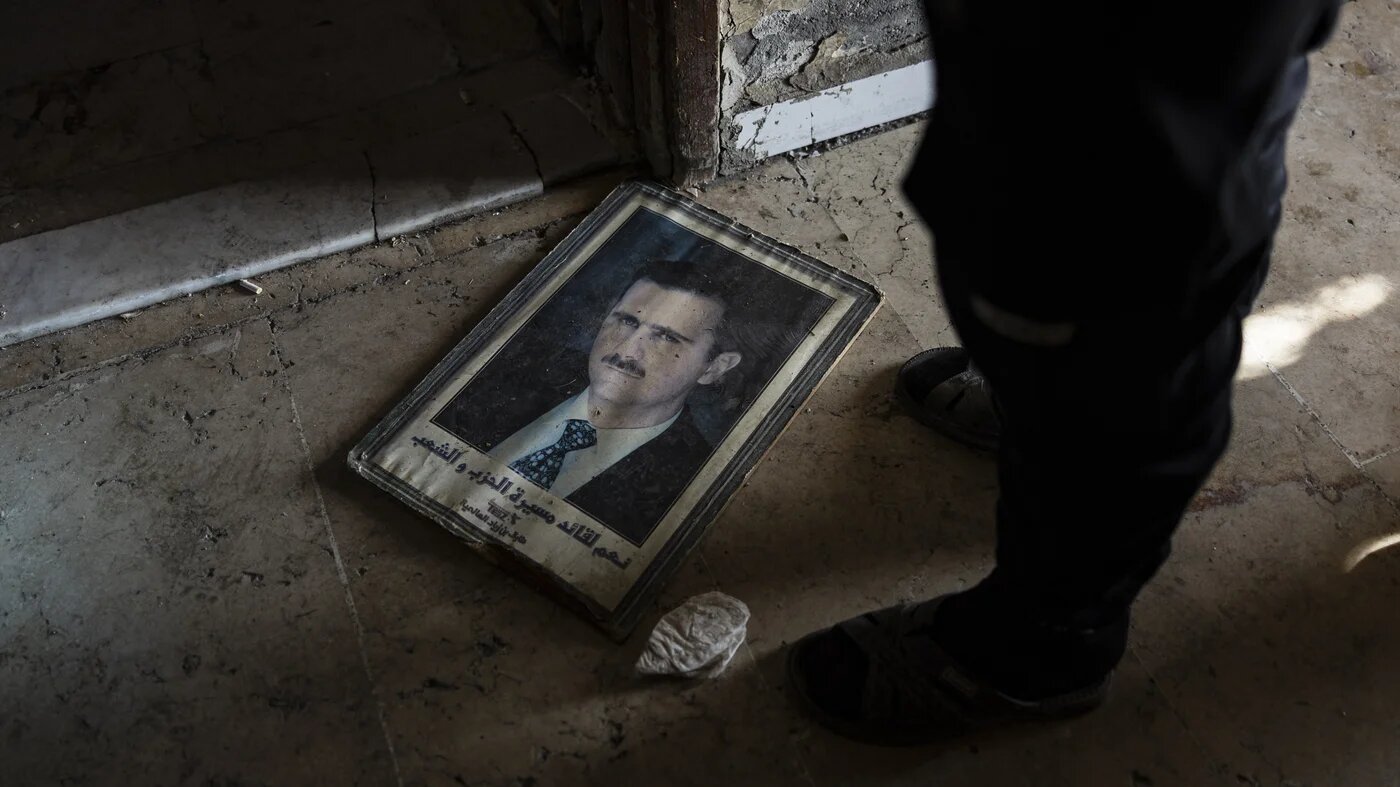A man stands next to a portrait of toppled Syrian President Bashar al-Assad in the capital Damascus on 20 December 2024 (Sameer al-Doumy/AFP)