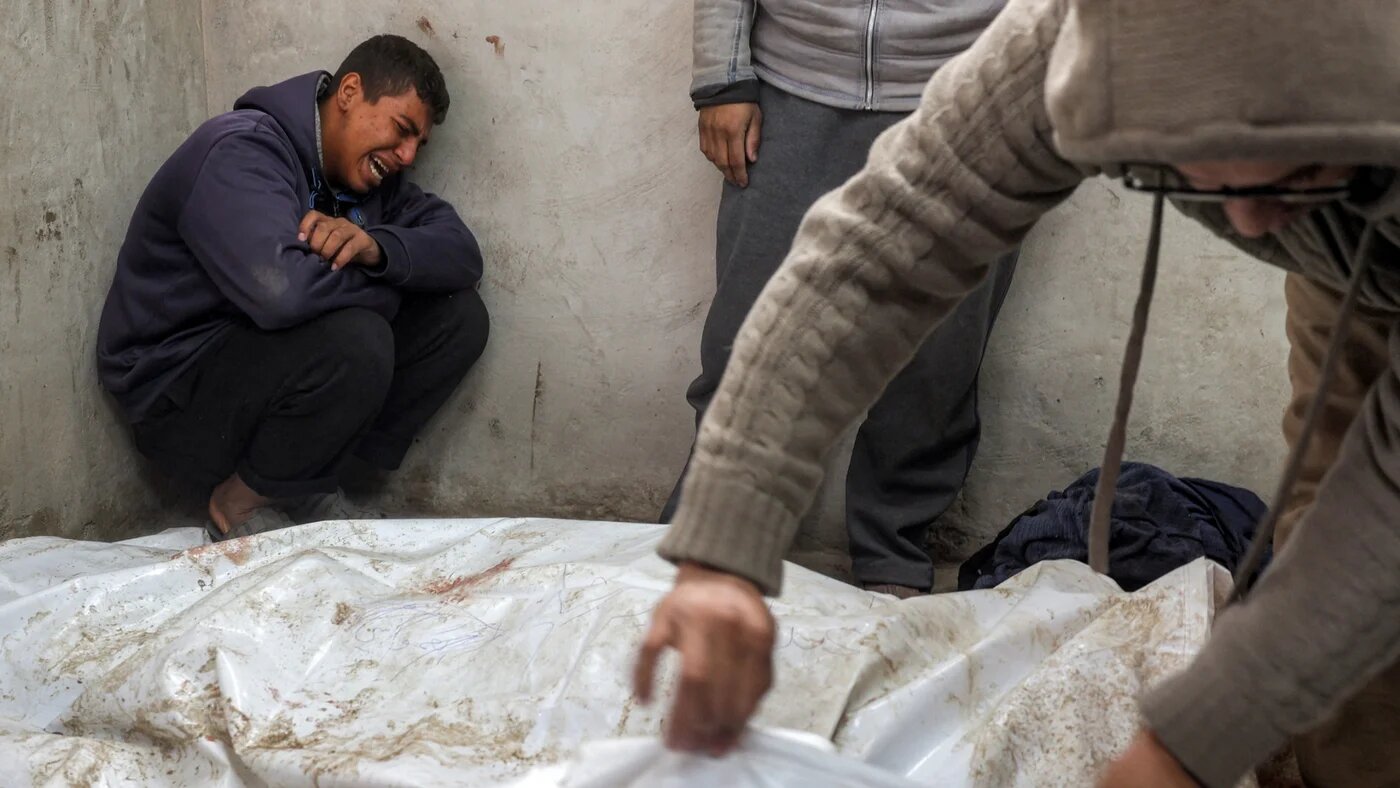 A boy mourns beside the bodies of Palestinians killed by Israeli forces at the morgue of al-Aqsa Martyrs Hospital in Deir al-Balah, central Gaza Strip, on 5 January 2025 (AFP/Eyad Baba)