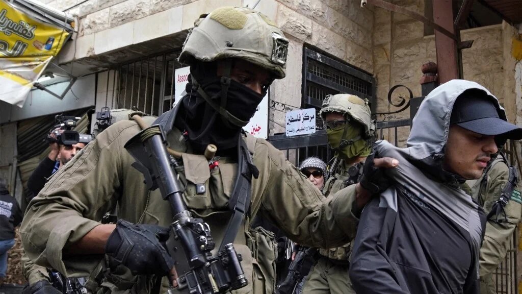 Israeli soldiers detain a youth after preventing access to Palestinians waiting to be let back into the Jenin camp for refugees during an ongoing military operation, on February 19, 2025