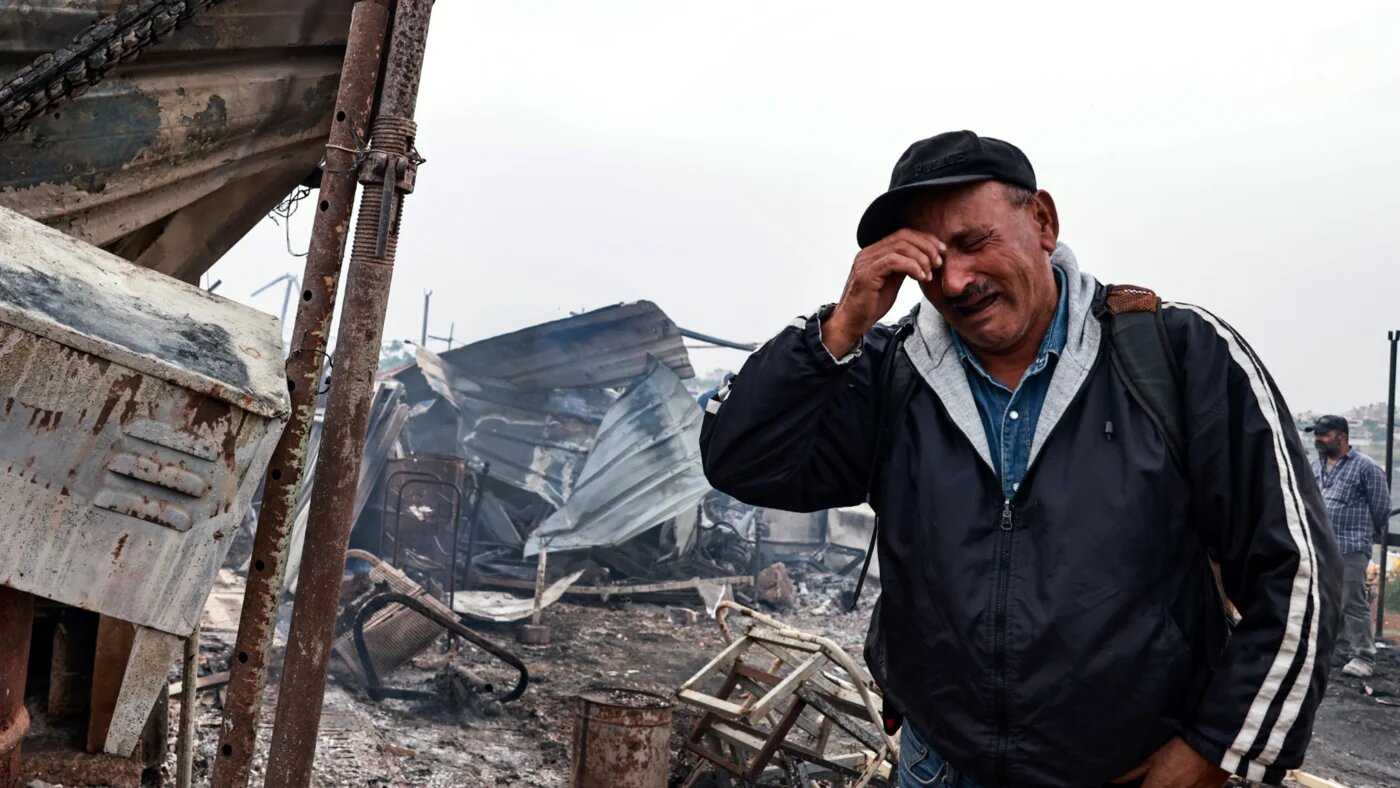 Palestinian farmer Ahmad Khalil reacts as he stands amid the charred remains of his agricultural installation, following an attack by Israeli settlers in the village of Sinjil, north of the occupied West Bank city of Ramallah on 23 April 2025 (AFP/Zain Jaafar)
