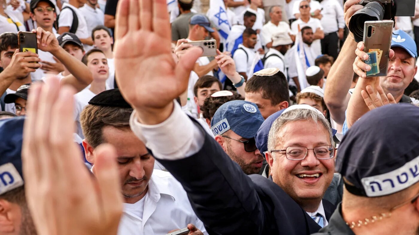 Israeli Minister of National Security Itamar Ben-Gvir, surrounded by Israeli policemen, waves to right-wing activists gathering outside the Damascus Gate of the walled Old City of Jerusalem on 26 May 2025 (Ahmad Gharabli/AFP)