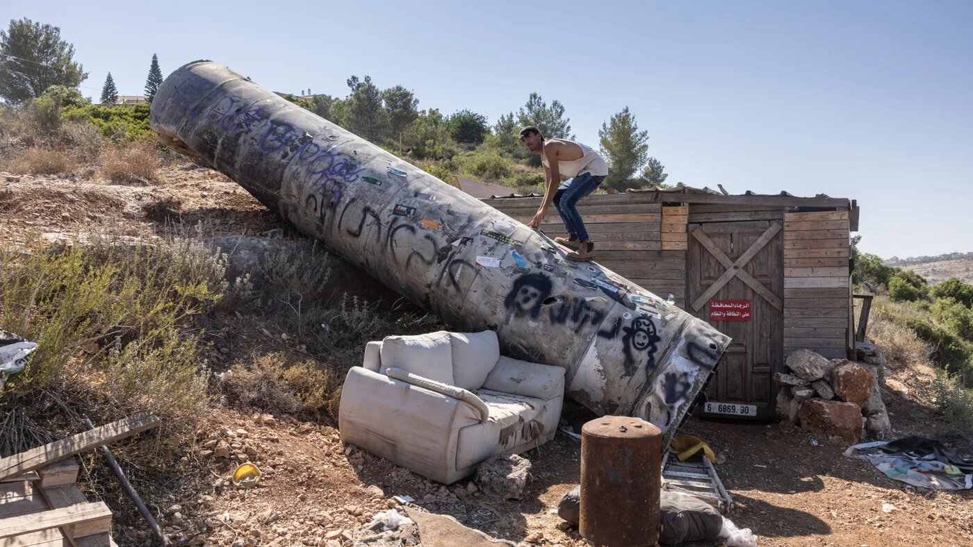 A man climbs on the remains of an Iranian missile in the Israeli settlement of Neria near Ramallah, in the occupied West Bank, on 29 June 2025, following the 12-day war between Israel and Iran (Menahem Kahana/AFP)
