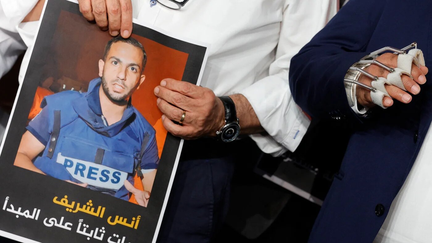 Wael Al-Dahdouh, Al Jazeera's bureau chief in Gaza, stands next to Al Jazeera anchor Mohamed Krichen holding the portrait of Anas al-Sharif during a moment of silence to honor Anas and four other colleagues (Karim Jaafar/AFP)