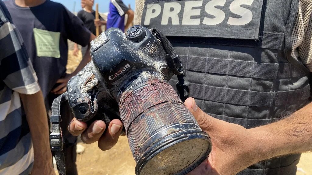 A journalist holds the blood-covered camera belonging Mariam Dagga, a Palestinian photojournalist killed in an Israeli strike on Nasser hospital in Khan Yunis in the southern Gaza Strip, during her funeral on 25 August, 2025. (AFP)