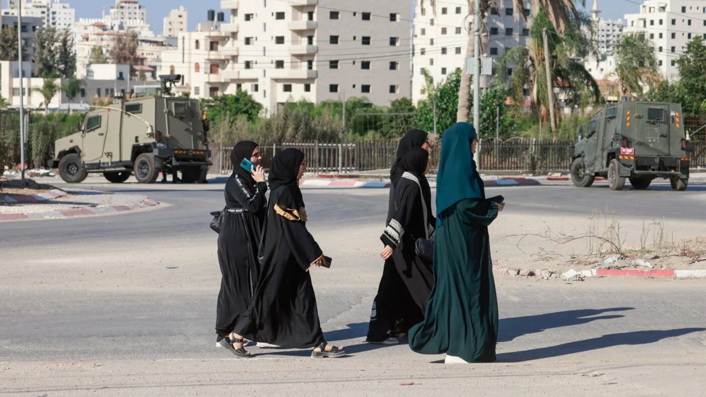 Palestinian women walk past Israeli troops in Tulkarem in the occupied West Bank on 11 September 2025 (Jaafar Ashtiyeh/AFP)