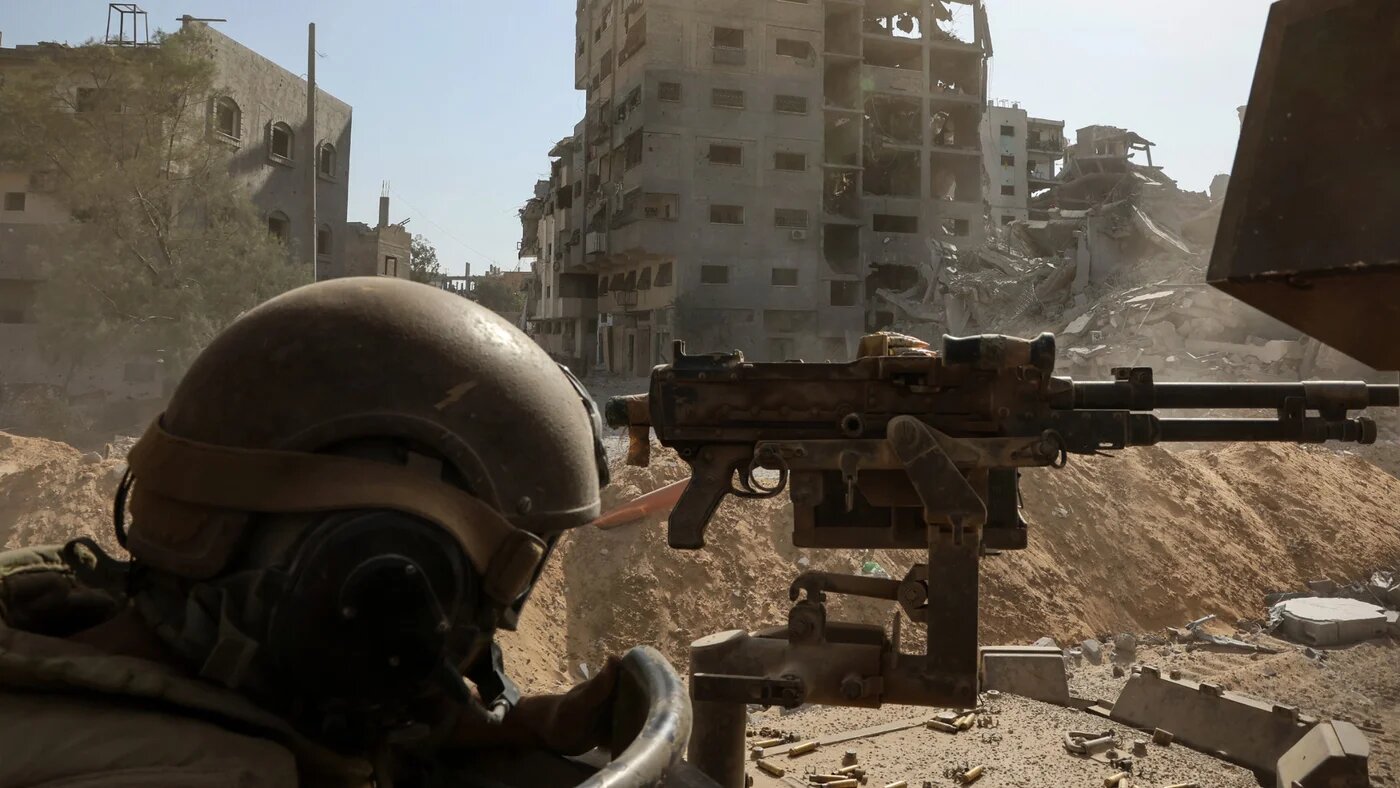 A soldier stands behind a mounted machine gun in Gaza City on 3 October 2025, in a photo taken during an Israeli army-controlled embed tour and edited under military supervision (AFP/Jack Guez)
