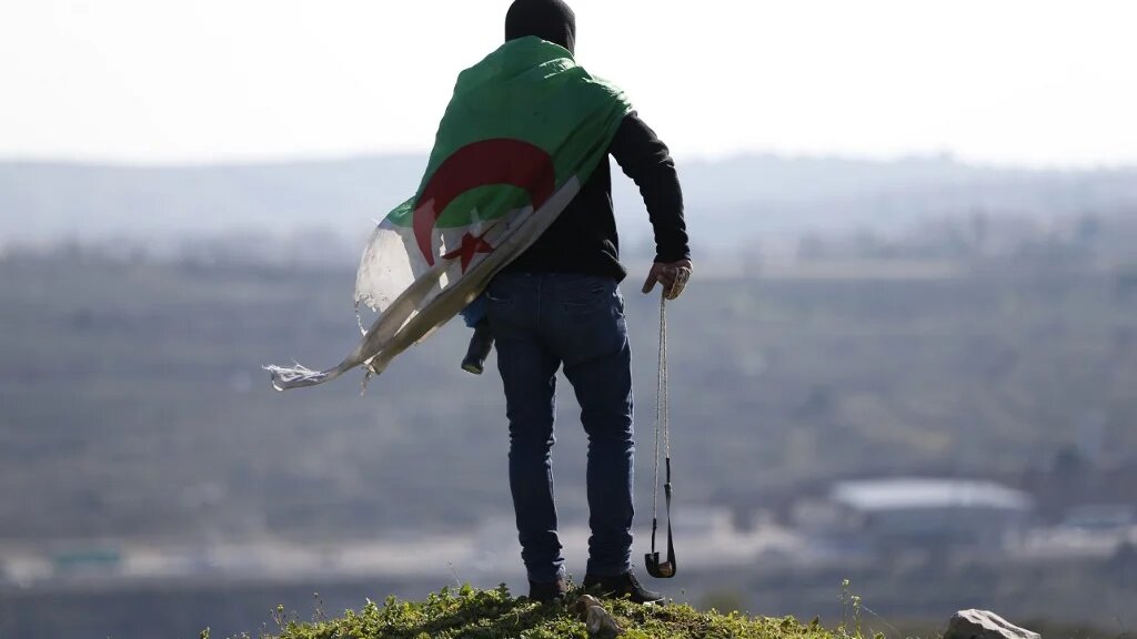 Un manifestant palestinien couvert du drapeau algérien, lors d’affrontements avec les forces israéliennes, le 12 février 2016 en Cisjordanie occupée (AFP) 