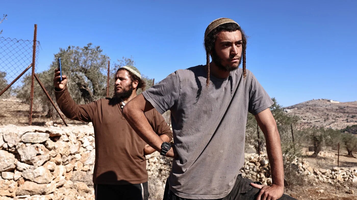 Israeli settlers stand in an olive grove as they attempt to disrupt the harvest carried out by Palestinian farmers and volunteers near the Palestinian village of Silwad, northeast of Ramallah in the occupied West Bank, on 29 October 2025 (AFP/Zain Jaafar)