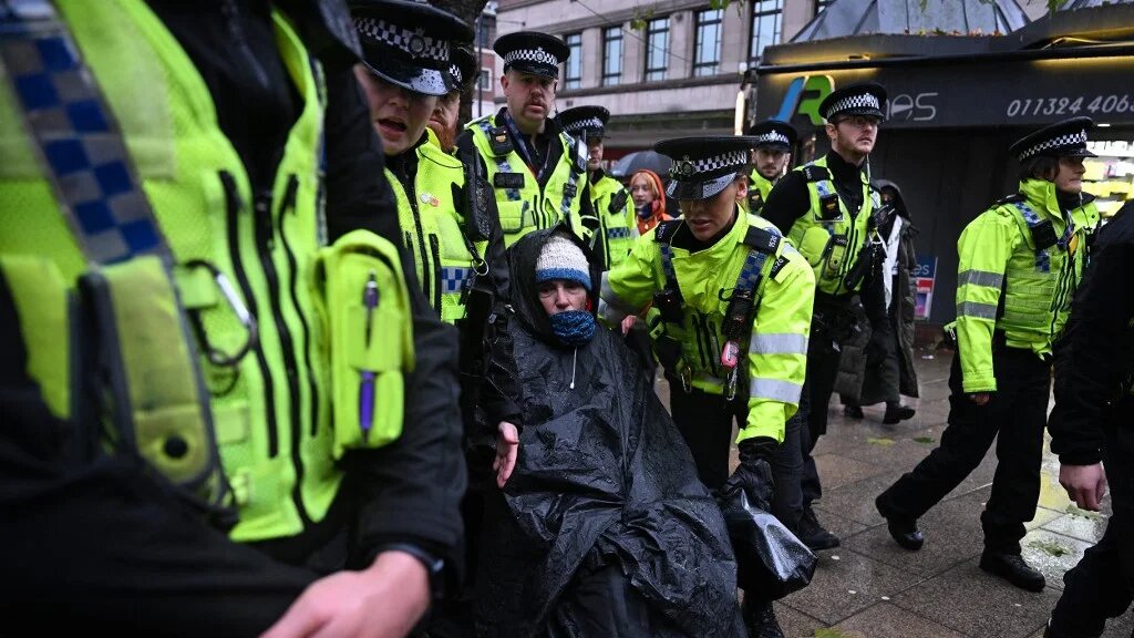 A protester in a wheelchair is escorted away by police officers after taking part in a demonstration in support of "Defend Our Juries" and their campaign against the ban on Palestine Action, in Leeds, northern England, on November 18, 2025.