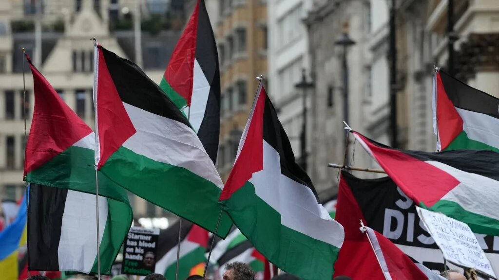 Protesters hold placards and wave Palestinian flags during a march organised by the Palestine Solidarity Campaign in central London on 29 November 2025, calling to "end the occupation, end apartheid and stop arming Israel".