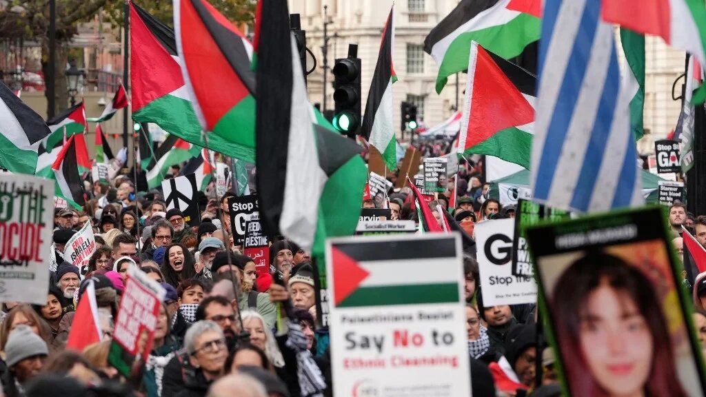 Protesters hold placards and wave Palestinian flags during a march organised by the Palestine Solidarity Campaign in central London on November 29, 2025.