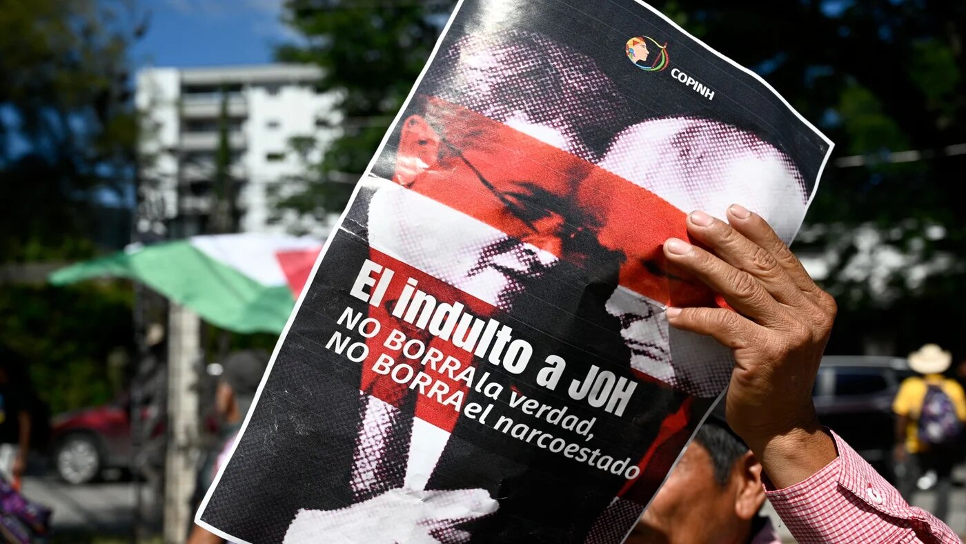 A protester in Tegucigalpa holds a banner reading 'The pardon for Juan Orlando Hernandez (JOH) does not erase the truth, does not erase the narco-state', 4 December 2025 (Orlando Sierra/AFP)