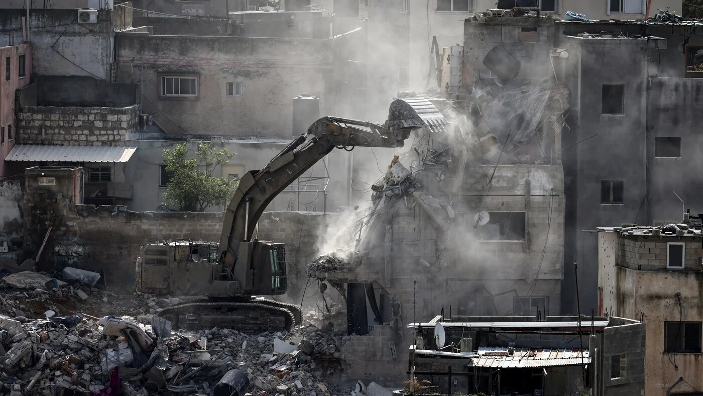 An Israeli military excavator tears down one of 25 residential buildings earmarked for demolition in the Nur Shams camp for Palestinian refugees near Tulkarem on 31 December 2025 (Zain Jaafar/AFP)