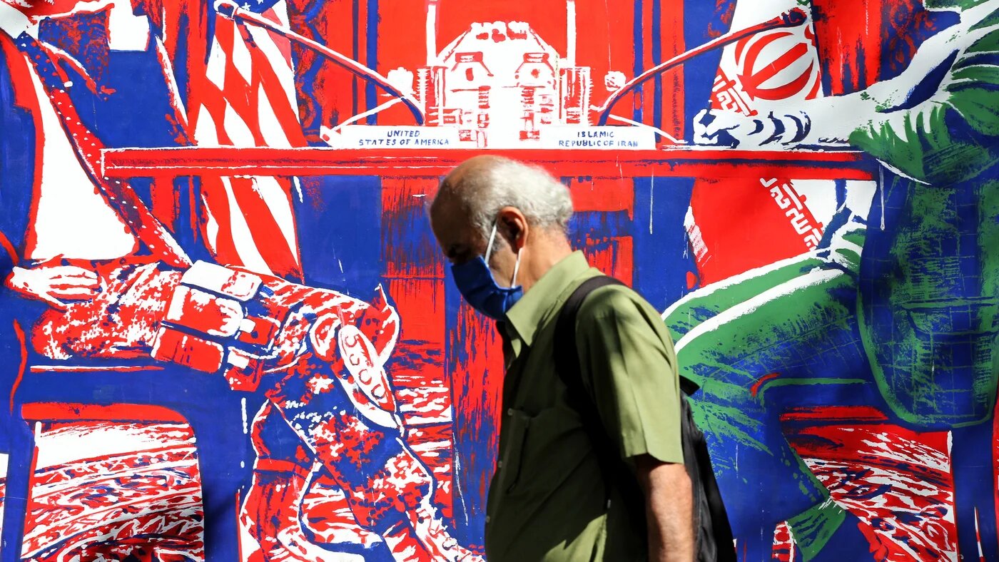 Un homme portant un masque passe devant une fresque peinte sur les murs d’enceinte de l’ancienne ambassade américaine à Téhéran, le 20 septembre (AFP)
