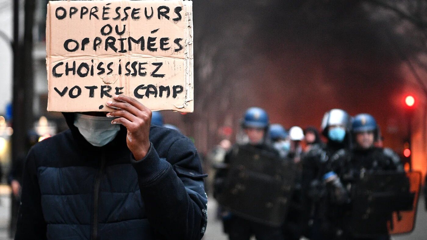 Un manifestant tient une pancarte lors d’une manifestation pour les « droits sociaux » et contre le projet de loi sur la « sécurité globale », à Paris, le 5 décembre 2020 (AFP)