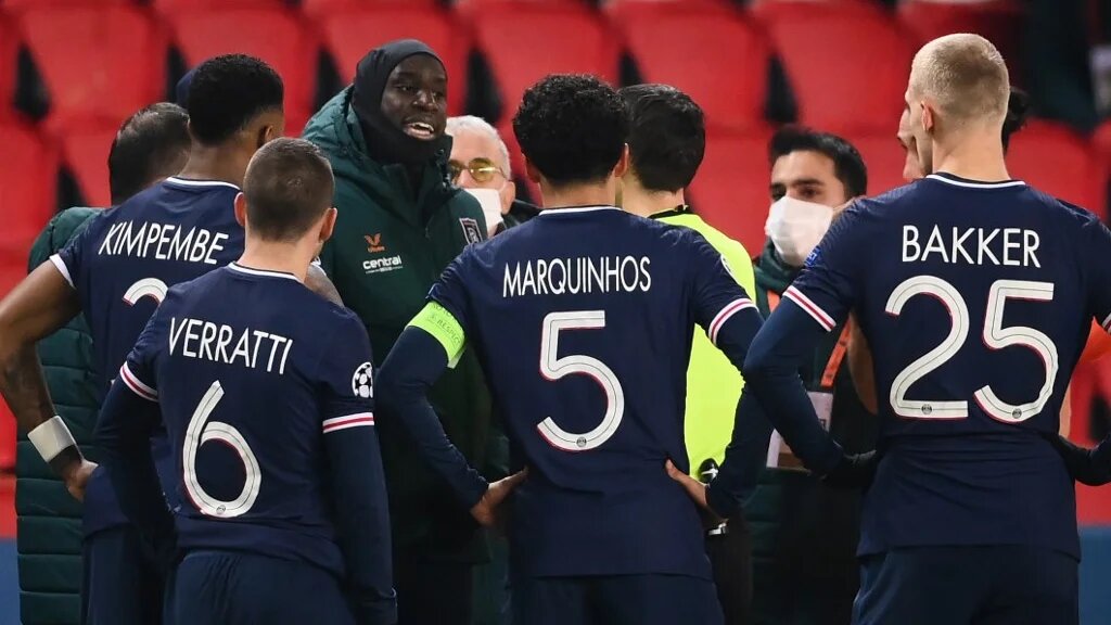 L’attaquant du Başakşehir Istanbul, Demba Ba (à gauche), s’entretient avec un des arbitres après la suspension du match contre le PSG, le 8 décembre 2020 (AFP)