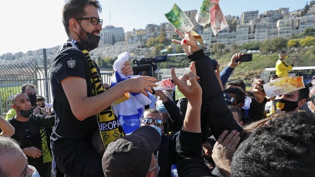 Une personne jette de l’argent à Moshe Hogg, propriétaire du club de football israélien Beitar, lors de la séance d’entraînement du club à Jérusalem, le 11 décembre 2020 (AFP)