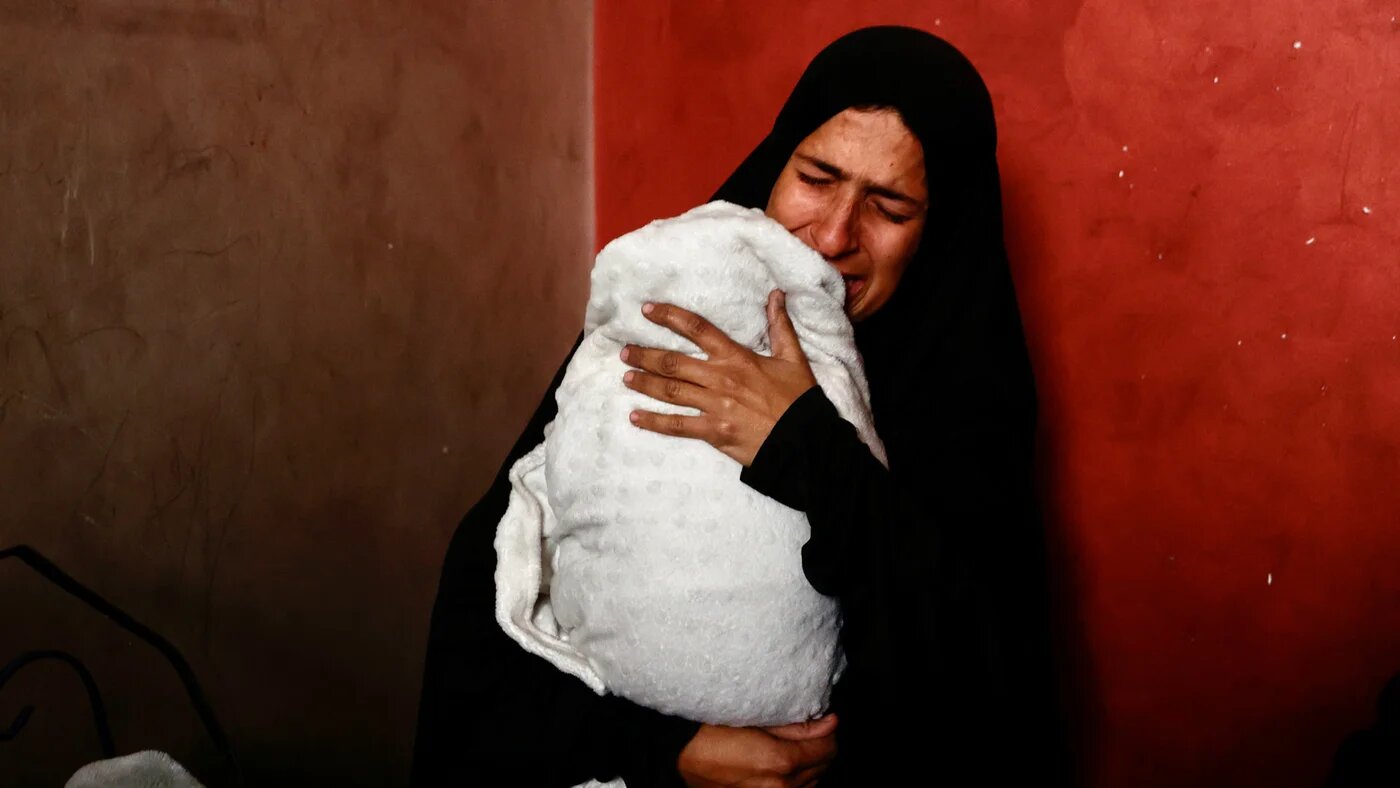 Hiba Abu Jarad, the mother of a three-month-old girl Shatha who died of hyperthermia, cries while holding Shatha's twin sister Nada in Gaza City on 20 January 2026 (Omar al-Qattaa/AFP)