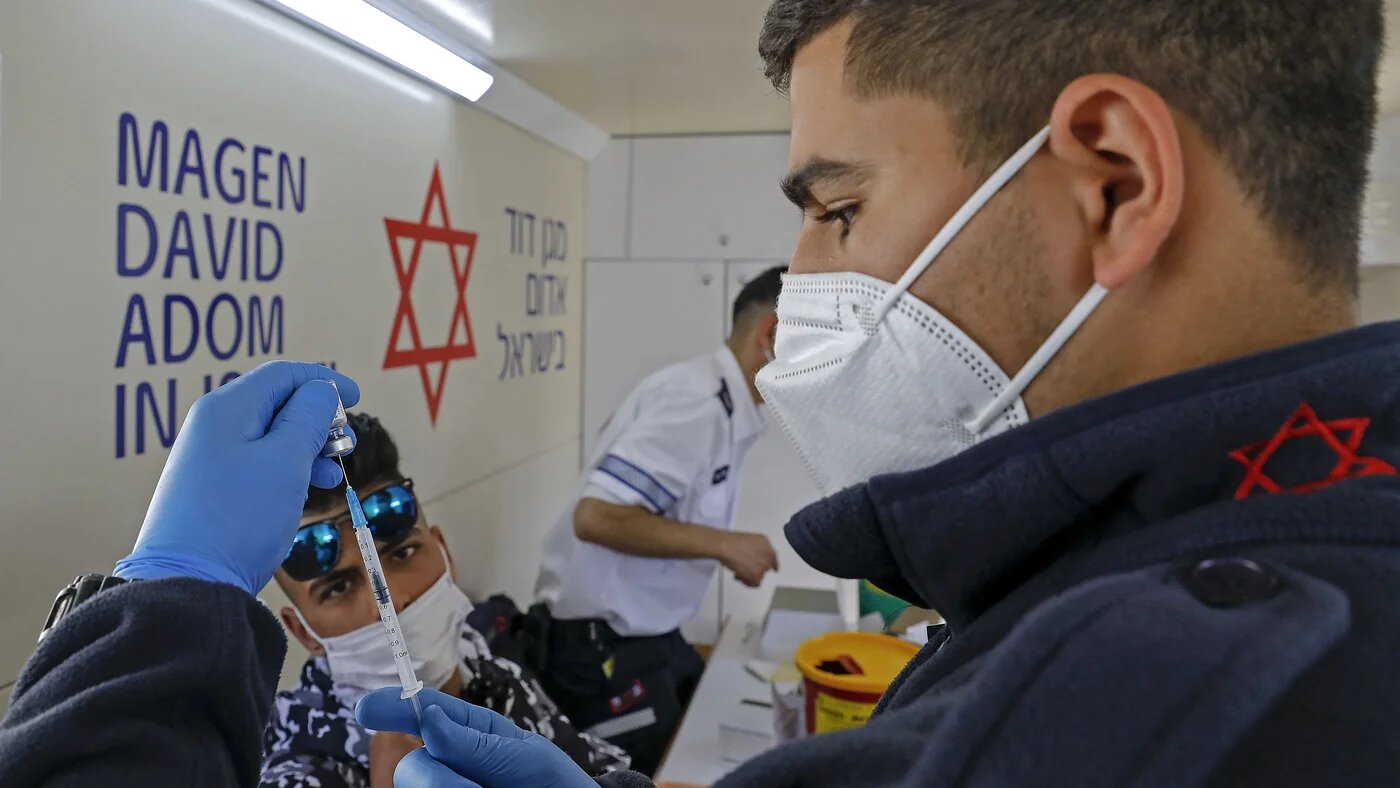 A paramedic with Israel's Magen David Adom medical services prepares a dose of the Pfizer-BioNTech COVID-19 vaccine to inoculate a Palestinian man in a mobile clinic on 26 February 2021, at the Damascus Gate in Jerusalem's Old City. (AHMAD GHARABLI / AFP)