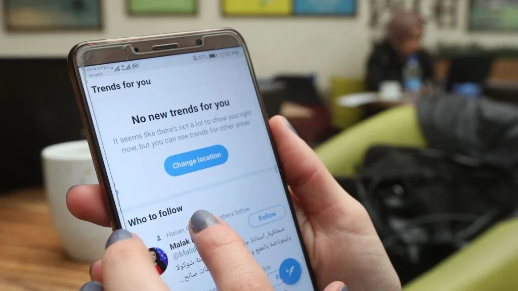 Zeina Shahla, a Syrian journalist, checks her twitter at a cafe in the capital Damascus on 1 March 2021. (AFP)
