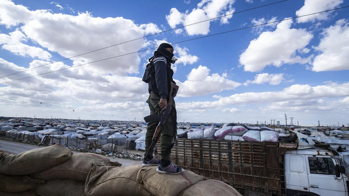 Un membre des forces kurdes de sécurité responsables du camp monte la garde alors qu’un groupe de familles syriennes est libéré du camp d’al-Hol, le 18 mars 2021 (Delil Souleiman/AFP)