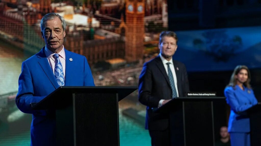 Reform UK leader Nigel Farage (L) speaks as deputy leader Richard Tice (C) and MP Suella Braverman (back R) look on during a party press conference in central London on February 17, 2026.
