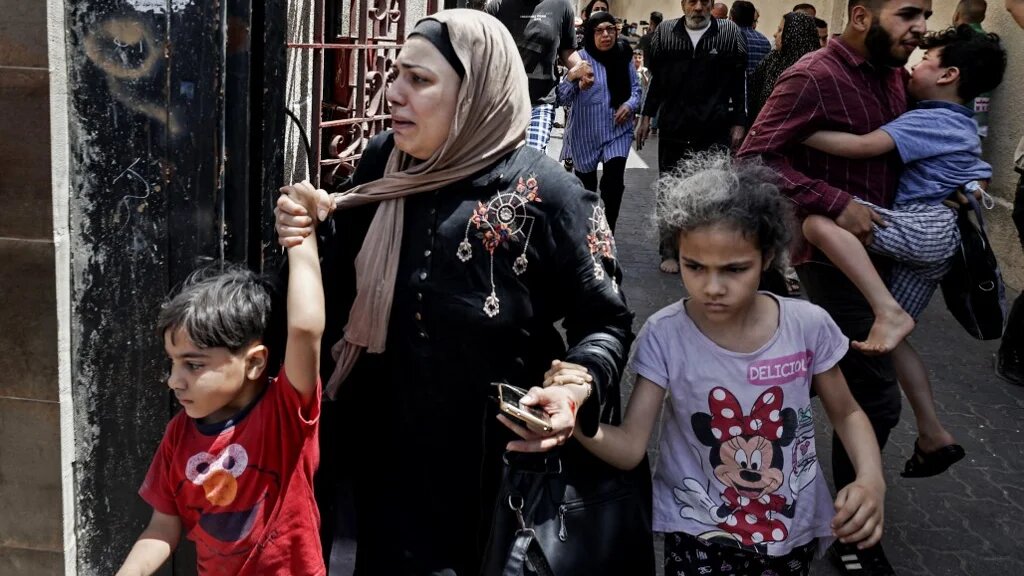 Des familles évacuent un bâtiment visé par les bombardements israéliens à Gaza, le 22 mai 2021 (AFP)