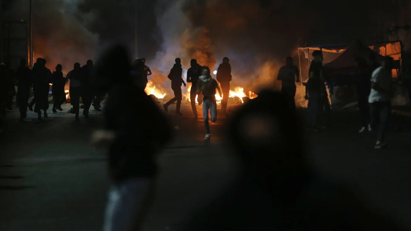 Palestinian demonstrators run away from gas