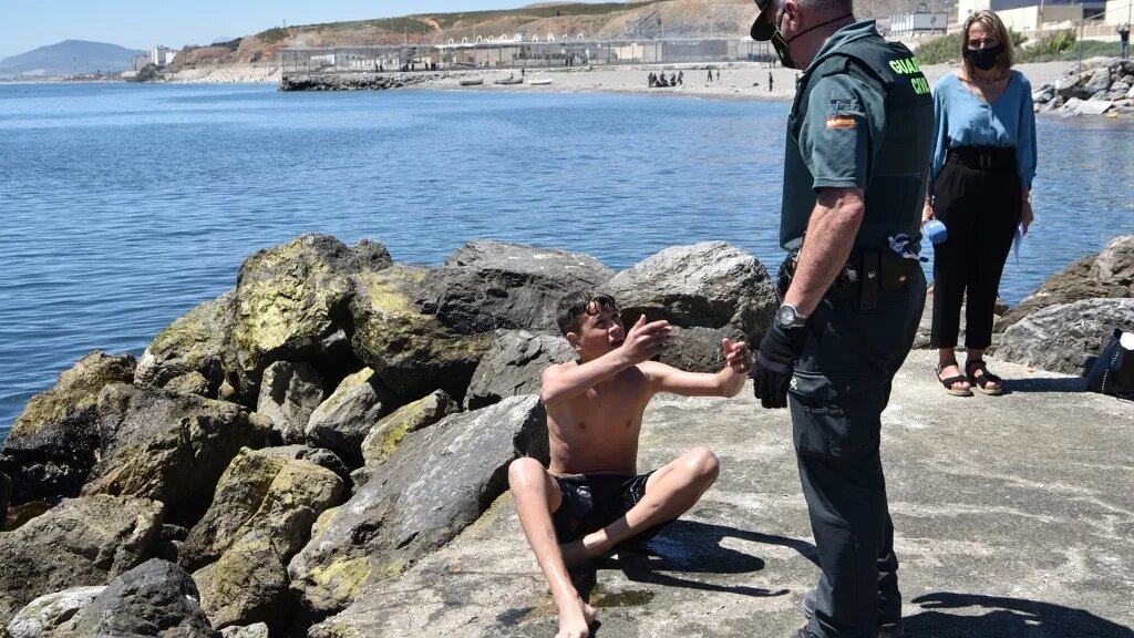 Un membre de la Guardia Civil (police à statut militaire) aide un migrant mineur à son arrivée par la nage à Ceuta, le 19 mai 2021 (AFP/Antonio Sempere)
