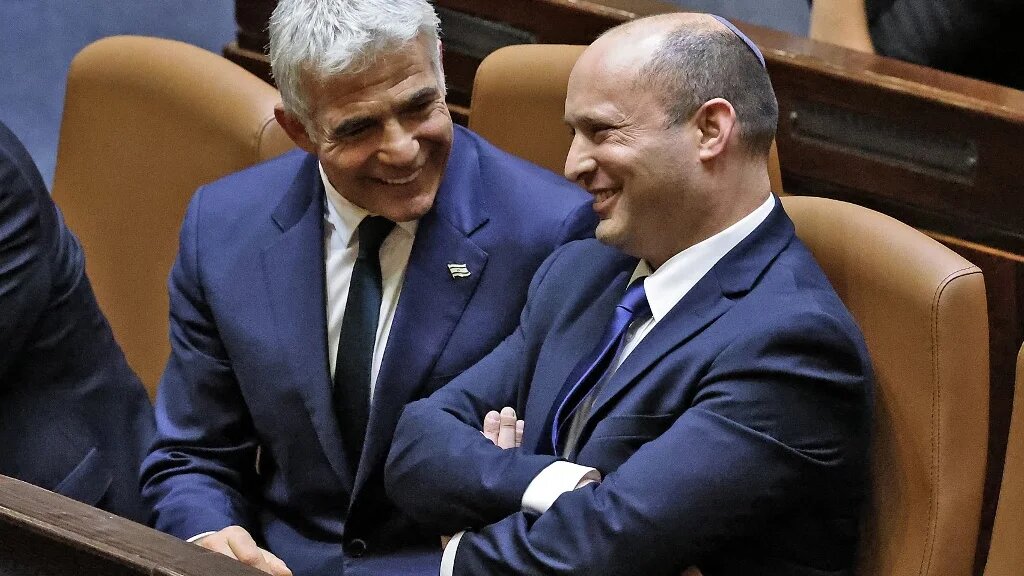 Le Premier ministre adjoint et ministre des Affaires étrangères d’Israël, Yaïr Lapid, s’entretient avec le Premier ministre Naftali Bennett dans l’hémicycle de la Knesset après une session extraordinaire pour voter sur un nouveau gouvernement, le 13 juin 2021 (AFP/Emmanuel Dunand)