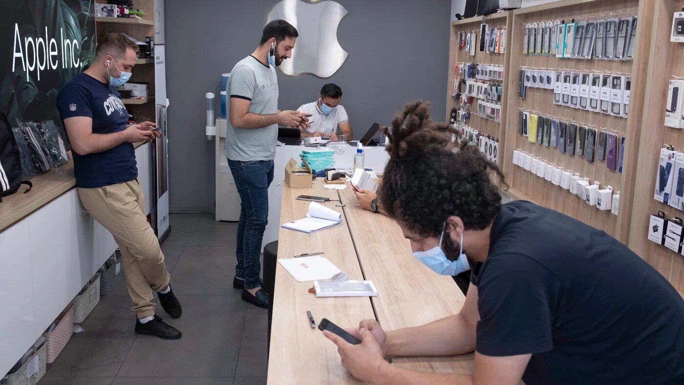Iranian staff use their smartphones at a shop in northern Tehran on 19 June, 2021 (AFP)