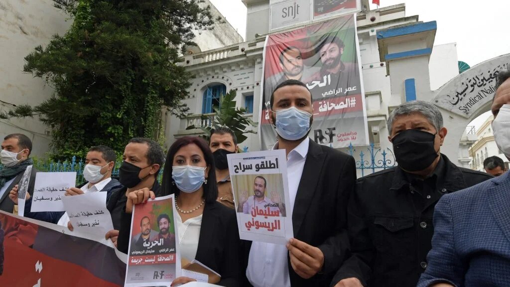 Des membres de l’Union des journalistes tunisiens posent avec des affiches en soutien aux journalistes marocains emprisonnés Omar Radi et Souleimane Raissouni, à ​​l’occasion de la Journée mondiale de la liberté de la presse à Tunis, le 3 mai 2021 (AFP/Fethi Belaïd)