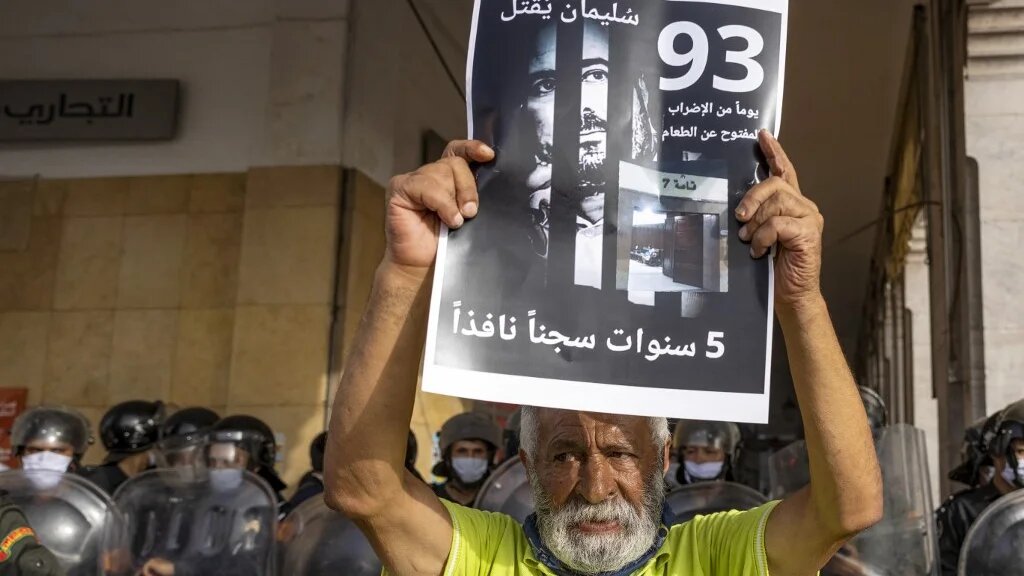 Un militant marocain tient une affiche avec la photo du journaliste marocain Souleimane Raissouni, condamné à cinq ans de prison pour « agression sexuelle », le 10 juillet 2021 à Rabat (AFP/Fadel Senna)