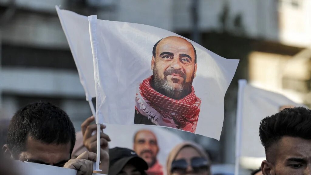 Demonstrators hold up images of late Palestinian activist Nizar Banat as they march during a protest in the city of Hebron in the occupied West Bank on 13 July 2021 (AFP)