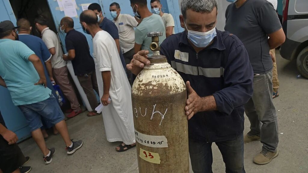 Des Algériens attendent de recevoir des bouteilles d’oxygène offertes par une entreprise privée pour les patients atteints de COVID-19 dans la ville de Blida (nord), le 28 juillet 2021 (AFP/Ryad Kramdi)